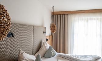 A modern bedroom with a cozy bed and stylish decorative elements. Natural light sources create a friendly atmosphere.