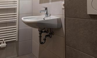A modern bathroom with a sink, a mirror, and a towel in soft colors. A towel rack hangs on the wall.