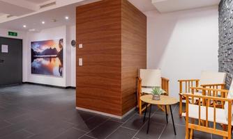 A modern foyer with wooden walls and stylish chairs. In the background, there is a large picture of a picturesque landscape.