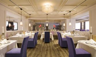 An elegant restaurant with stylish tables and blue chairs. Soft lighting and modern furnishings create an inviting atmosphere.