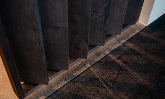 A modern door with vertical wooden slats and an elegant floor. The shadows create an interesting play of light in the room.