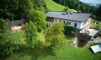 A beautiful, modern house surrounded by green meadows and trees. The landscaping offers plenty of outdoor space and a tranquil atmosphere.