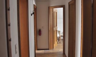 A modern hallway with bright walls and wooden flooring. There are several doors leading to different rooms.