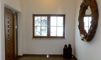 A bright entrance area with a large window view to the outside. A round mirror is hung on the wall and there are two decorative objects.