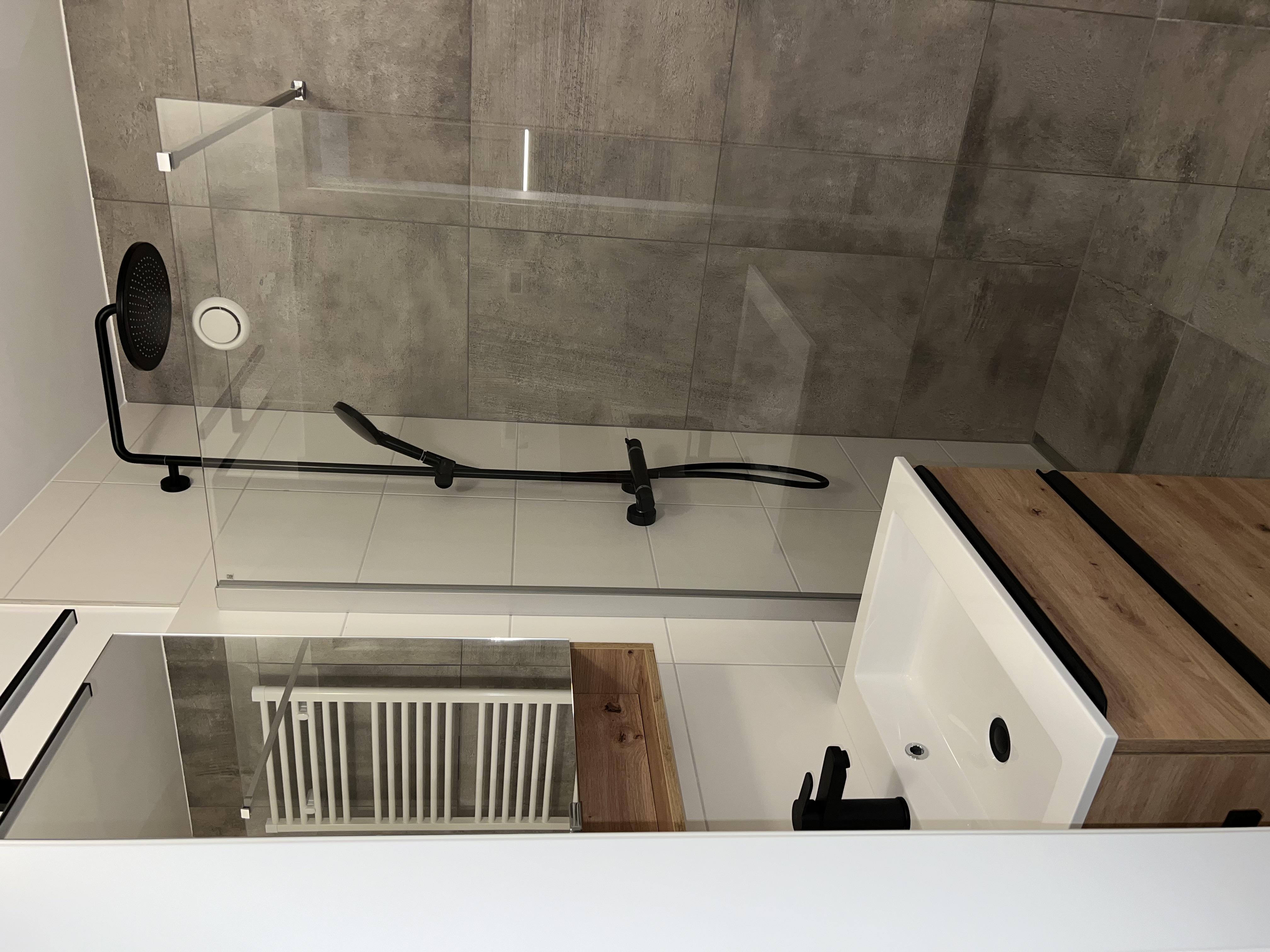 A modern bathroom with a walk-in shower and an elegant wood vanity combination. The walls are done in gray tiles, and the design is simple and stylish.
