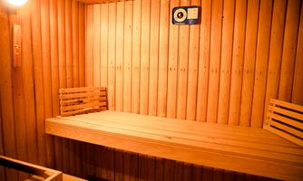 A cozy sauna room with wooden paneling and benches. Soft light creates a relaxing atmosphere.