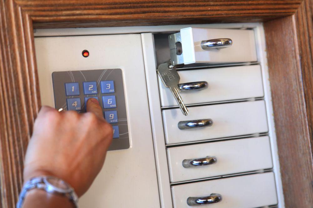 A finger taps on a keypad at a locking system. Next to it are several compartments with locks.