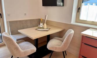 A cozy dining area with a wooden table and comfortable chairs. The room has bright walls and a window that lets in a lot of light.