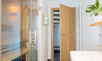 A bright and modern room with a sauna on the left side. The door is open and leads to another area of the house.