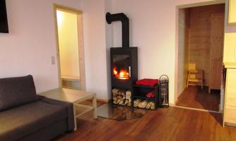A cozy living room with a modern fireplace and a sofa. The hardwood floor creates a warm atmosphere.