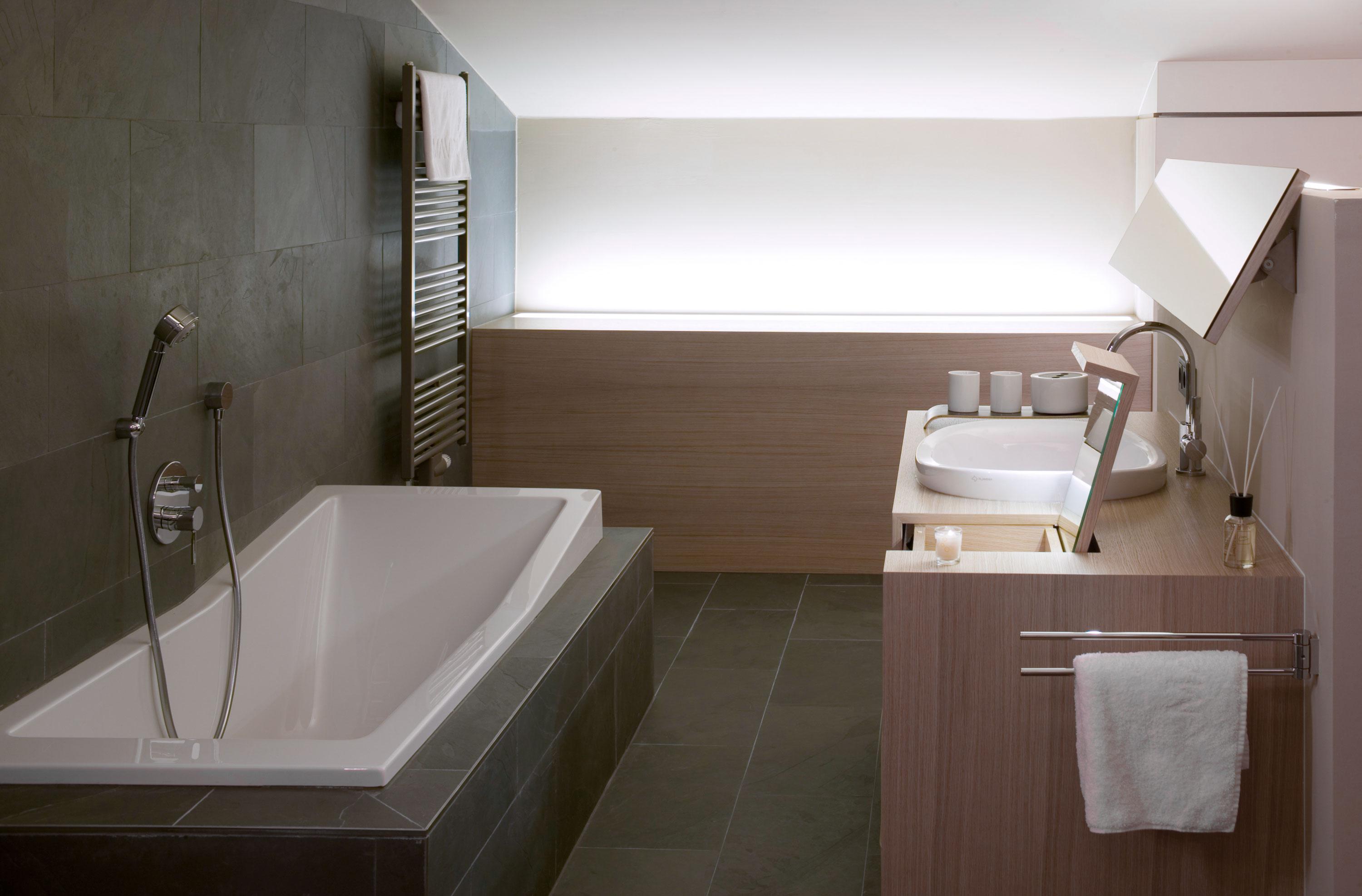 A modern bathroom with a freestanding bathtub and an elegant sink. The walls are in neutral colors, and the light is soft.