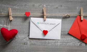 A string with clothespins holds a white envelope and a red envelope, surrounded by red hearts. The envelopes give the scene a romantic mood.