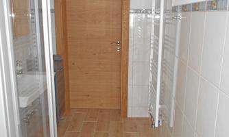 A modern bathroom with tiled floor and a shower. The wood and white walls create a bright, inviting atmosphere.