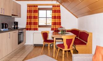 A cozy kitchen with a dining area and a large window. The decor is simple and modern, with a warm color scheme.