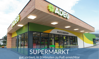 A modern supermarket with a large glass front and friendly wooden architecture. It is well-stocked and a three-minute walk away.
