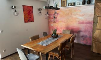 An elegant dining area with a large wooden table and six chairs. The walls are adorned with artwork and decorative objects.