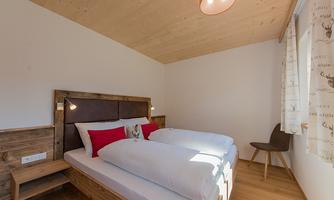 A bright bedroom with a double bed and wooden paneling. The cozy decor creates an inviting atmosphere.