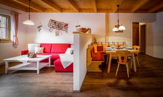 A cozy living room with a red sofa and a wooden table. The space has a warm atmosphere and a modern decor.