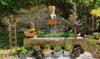 A beautifully designed garden landscape with a wooden log as a planter. Various plants and decorative elements are arranged around the log.