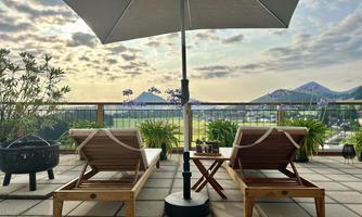 A terrace with two loungers, an umbrella, and flower pots overlooking the Salzkammergut and a vacation feeling
