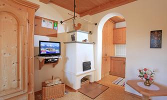 A cozy living space with wooden details and a television. The open kitchen features warm wooden tones and an inviting character.