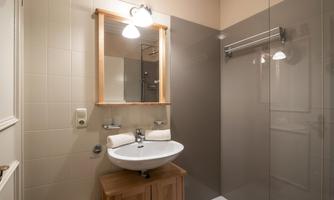 A modern bathroom with a shower, a sink, and a large mirror. The walls are bright and the decor is simple and stylish.