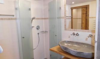A modern bathroom with glass shower cabins and a stylish stone sink. The walls are bright, and the atmosphere is friendly and inviting.