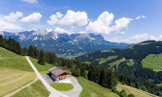 A beautiful mountain panorama with green meadows and a solitary chalet. The clouds in the sky give the scene a picturesque charm.