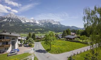 A picturesque landscape with majestic mountains in the background. In the foreground, there is a peaceful village with green meadows and trees.