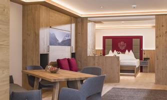 A modern suite with wood paneling and elegant furnishings. The room features a dining area and a comfortable bed.