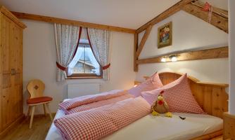 A cozy bedroom with wooden furniture and checkered bedspreads. The atmosphere is warm and inviting.