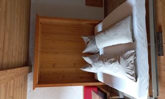 A cozy bedroom with a fold-down bed and white pillows. The walls are designed in a light wood tone.