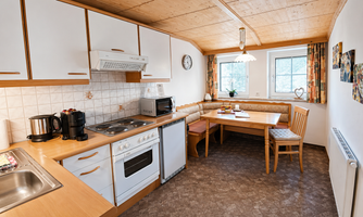 A modern kitchen with large windows. The dining area with a table and chairs invites you to linger.