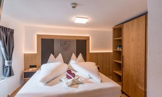A modern bedroom with a large bed and wooden cabinets. The cozy atmosphere is emphasized by warm lighting and simple decorations.