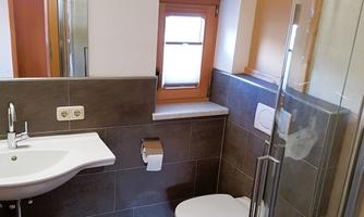 A modern bathroom with a sink, a toilet, and a shower. The design is simple and functional with neutral colors.