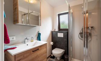 A modern bathroom with a shower and wooden furniture. Bright colors create an inviting atmosphere.