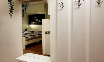 A modern hallway with a white mirror and a shelf. Practical coat hooks are hanging on the wall.