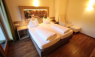 A cozy room with two single beds and a wooden floor. The atmosphere is warm and inviting, perfect for relaxing.