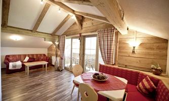 A cozy living space with wood paneling and a large window. There is a dining area and a seating area with red sofas.