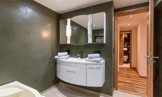 A modern bathroom with an elegant sink and mirror. The space has a warm color scheme and features soft lighting.