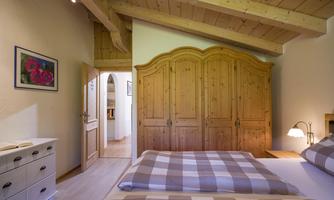 A cozy bedroom with wood paneling and a large wardrobe. The walls are light, and there is a window that brightens the room.