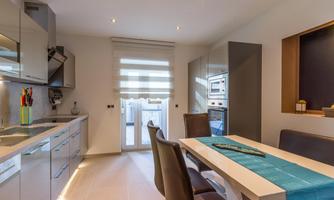 A modern kitchen with a dining table and elegant chairs. Bright colors and plenty of natural light create an inviting atmosphere.
