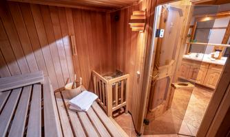 A cozy sauna with wooden walls and benches. In the background, a towel and a bucket can be seen.