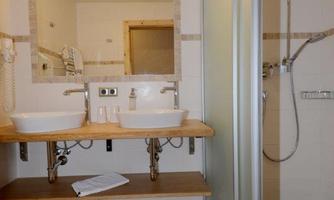 A modern bathroom with two sinks and large mirrors. The shower is separated by a glass wall.