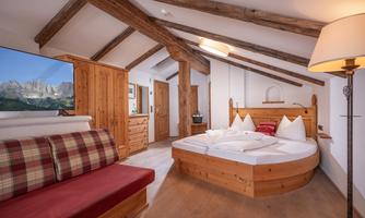 A cozy bedroom with wood decor and a round bed. The room has a warm atmosphere and features a sitting area and a television.