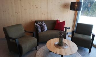 A cozy seating area with a sofa and two chairs in green. The round table in the middle is adorned with a decorative plant and a modern lamp.