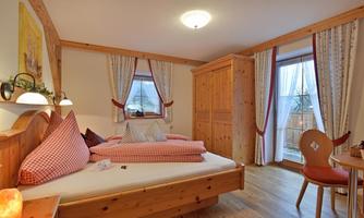 A cozy room with wooden details and two beds.  
Large windows let in a lot of light and offer a view outside.