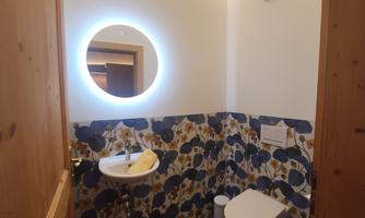 A modern bathroom with a stylish, floral wall covering. The room is well-lit and features a sink and a toilet.