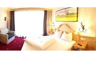 A cozy hotel room with wooden decor and a large window. There is a TV, a seating area, and a large bed.