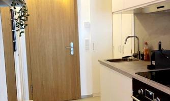 A modern kitchen with bright walls and wooden details. The room features a spacious work surface and a door that leads to another room.